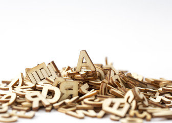 A letter on top of a pile of wooden letters. Isolated on white. Copy scape.