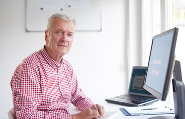 Elderly professional man using his computer in the office