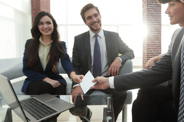 Business card being passed over between a male and female busine