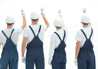 Obraz premium rear view.team of construction workers paint a wall.