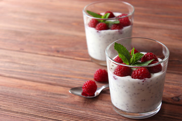 chia pudding in a glass with raspberries on a wood background.