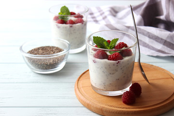 chia pudding in a glass with raspberries on a light wooden table. Proper nutrition, super food