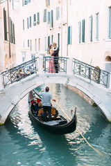 Gondole in chanel of Venice, Italy. Lovers hugging and kissing stand on the bridge of the canal © sofiko14