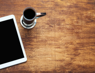 Tablet computer and coffee on wooden background. View from th top