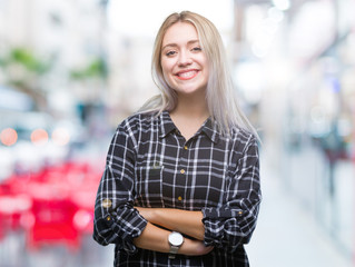 Young blonde woman over isolated background happy face smiling with crossed arms looking at the camera. Positive person.