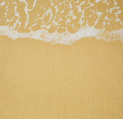Soft wave of sea foam on sandy beach. Background, texture