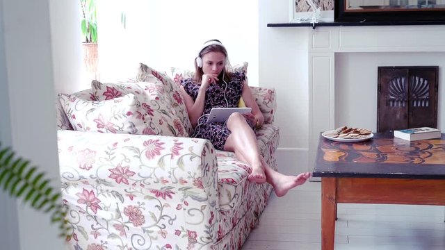 Young cute woman watching movie by table at home
