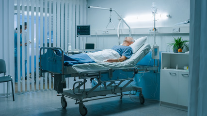 In the Hospital Senior Patient Rests, Lying on the Bed. Recovering Man Sleeping in the Modern...