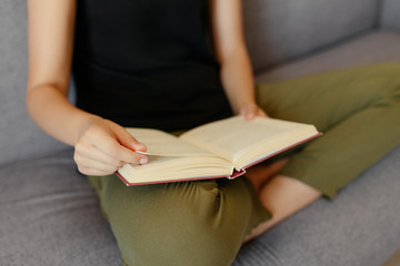 Close-up view of female hands reading and flipping the pages of a book. Hobby concept. At home.