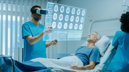 Doctor Wearing Virtual Reality Headset and Holding Joysticks Cures Senior Patient who is Lying in...