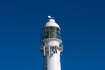 Close up of a lighthouse against a blue sky.