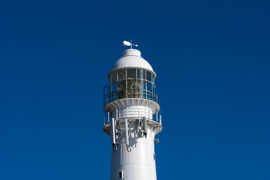 Close up of a lighthouse against a blue sky. - Powered by Adobe