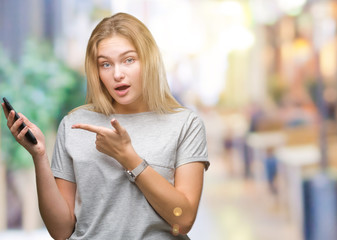 Young caucasian woman sending message using smartphone over isolated background very happy pointing with hand and finger