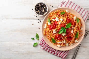 Spaghetti pasta with tomato sauce, mozzarella cheese and fresh basil in plate on white wooden...