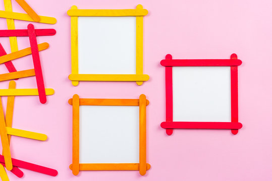 blank photo frame made of color popsicle wood sticks on pink background
