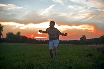 Man in the field at sunset enjoy life smiling, happy with victory,  good news, screams, freedom.