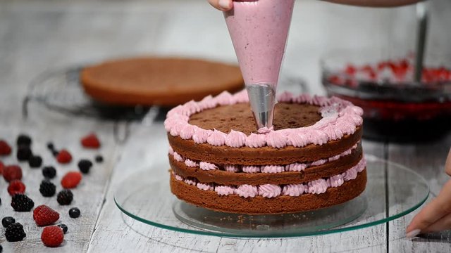Confectioner is decorating chocolate cake.