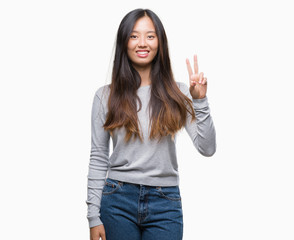 Young asian woman over isolated background smiling with happy face winking at the camera doing victory sign. Number two.