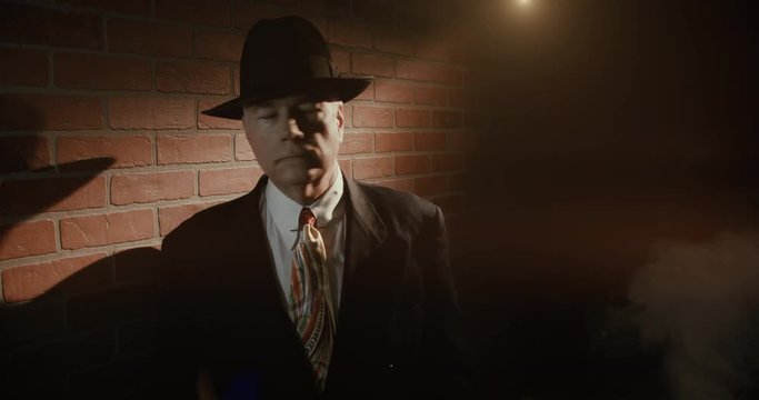 Film noir 1940s style scene with a mature man in a fedora in a dark alley looks around and checks his wristwatch as if waiting for someone.