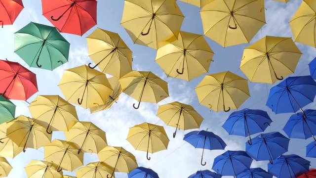 Relaxing movements of parasols in the rows. Colorful umbrellas on the wind. Slider shot
