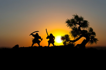 Silhouette of two samurais in duel. Picture with two samurais and sunset sky. Selective focus
