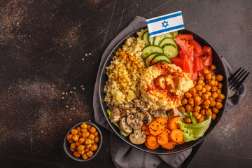 Buddha bowl with vegetables, mushrooms, bulgur, hummus and baked chickpeas. Dark background, top view. Israeli food concept.
