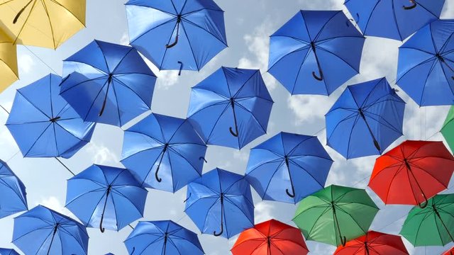 Many rows of colourful decorative umbrellas on the wind. Slider view
