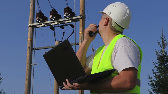 Electrician watching high voltage transformer and using walkie talkie