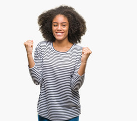 Young afro american woman over isolated background celebrating surprised and amazed for success with arms raised and open eyes. Winner concept.