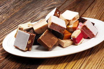 Delicious traditional Italian festive torrone or nougat with nuts on wooden background. Soft nougat blocks with almonds and in diffrent colors. Italian sweets