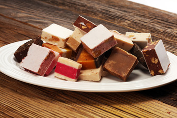 Delicious traditional Italian festive torrone or nougat with nuts on wooden background. Soft nougat blocks with almonds and in diffrent colors. Italian sweets