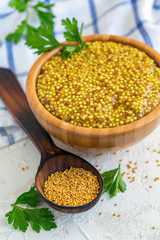 Grain mustard in a wooden bowl close-up.