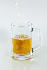 Foam rises in a glass when beer is poured on an isolated white background.