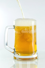 Beer is poured in a glass on an isolated white background.