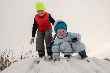 Fototapeta na wymiar Two brother's boys are having fun riding a new yellow sled. Children, best friends are happy on a winter day. Active rest with children. Casual boy's fashion