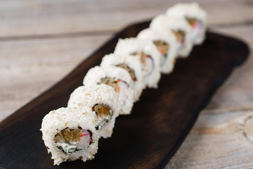 Tasty  traditional food, Japanese culture. Sushi rolls with crab meat, cucumber and cream cheese, covered with sesame, restaurant serving