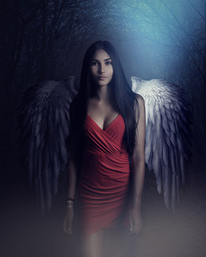 A beautiful white archangel descended from heaven. A girl with a sexy red dress with huge white wings. Artistic Photography