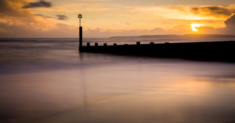 Fototapeta na wymiar Sunset long exposure shot of sea front groyne with very smooth sea