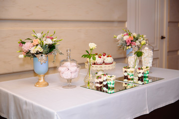 Candy bar, a table with sweets and desserts on the table. Buffet with delicious cupcakes, cake pops, biscuits, flowers.