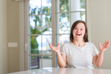 Down syndrome woman at home very happy and excited, winner expression celebrating victory screaming with big smile and raised hands