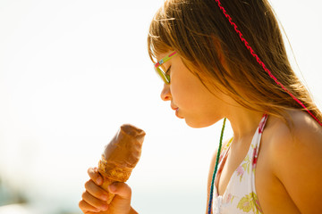 Toddler girl in eyeglasses eating ice cream