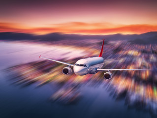 Airplane with motion blur effect is flying over sea coast at night. Landscape with passenger...