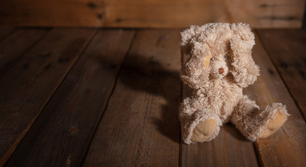 Child abuse.Teddy bear covering eyes, dark empty background, copy space