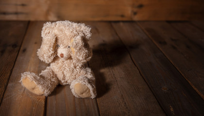 Child abuse.Teddy bear covering eyes, dark empty background, copy space