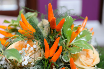 Chilli peppers between orange roses and green leaves