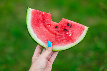 Summer mood. Girl holding slice of watermelon in hands with green summer garden bokeh background....