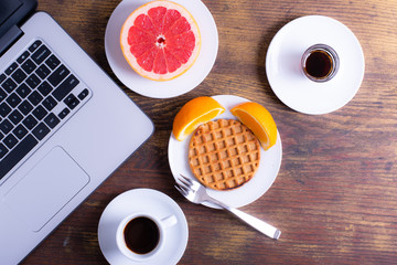 Breakfast With Grapefruit, Coffee, Waffle, Syrup and Orange On Wooden Table With Fork.