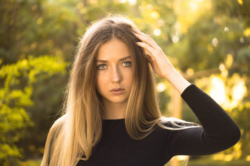 Beautiful serious concentrated girl student posing in the park outdoors on grass looking camera.