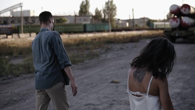Halloween horror filming concept. Picture of creepy male and female ghost or zombie walking with wounded face. Male zombie falling down on the ground. Industrial, abandoned town around