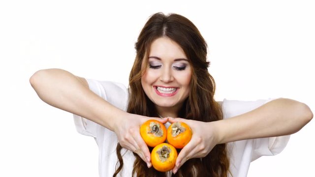 Woman toothy smile brunette girl holding  persimmon kaki fruits in hands, isolated on white. Healthy eating, vegetarian food, diet concept